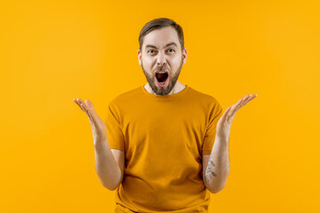 Studio portrait of a young emotional soccer supporter man cheering for his favourite team, isolated over bright colored orange yellow background