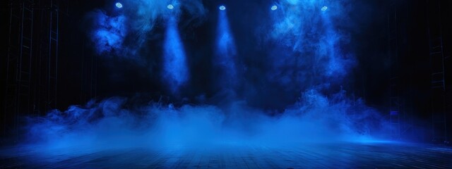 Black stage with blue smoke below, like fog on the floor. In a dark room.	
