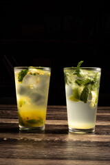 Refreshing mojito. Fresh lime citrus juice or soft drink with ice and mint leaves. Glass with dietary vitamin product on black background. Organic antioxidant cocktail. Copy space