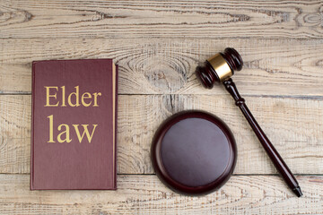 Law concept - Elder law. Open law book with a wooden judges gavel on table in a courtroom or law enforcement office on the wooden background. Copy space for text. - 798134209