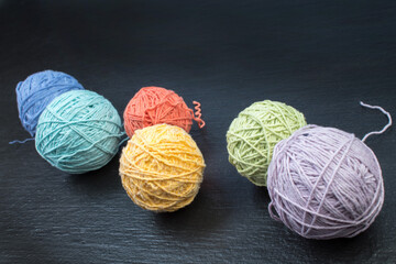 Colored yarn on a black background. Skeins of wool yarn for knitting. Balls of wool of different colours for handmade knitting on a wooden background with copy space for ad. - 798134444