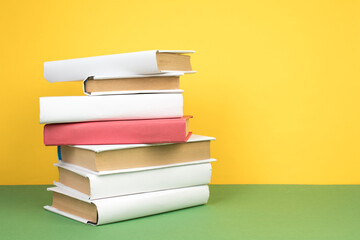 Books stacking. Open hardback books on wooden table and green background. Back to school. Copy space for ad text.