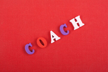 COACH word on red background composed from colorful abc alphabet block wooden letters, copy space...