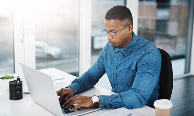 Typing, serious and black man by computer in office, workspace or desk professional in creative...