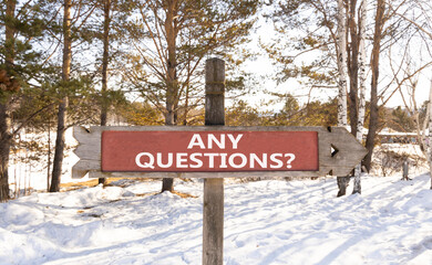 Any questions symbol. Concept words Any questions on beautiful wooden road sign. Beautiful forest snow blue sky background. Business and Any questions Q and A concept, copy space.