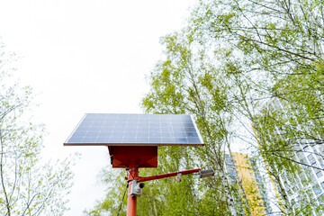 A solar panel rests on a crimson pole under the vast sky
