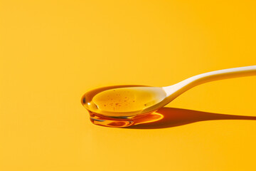 Golden Honey Dripping From a Spoon Against a Yellow Background