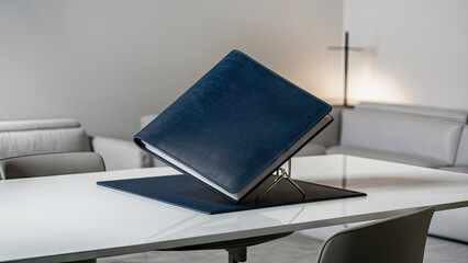  A stunning image of a pristine blue leather folder elegantly positioned on a pristine white desk in a minimalist room.