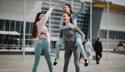 Two women in sportswear doing stretching exercises on a city street, preparing for a fitness...