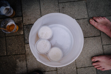 Dobele, Latvia - August 18, 2023 - Top-down view of three foam-topped beers in plastic cups inside...