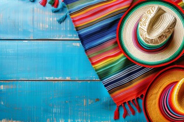 Brightly colored Mexican sombrero hats and a striped serape blanket on a weathered blue wooden surface. Perfect for themes such as holidays, culture and travel. Banner