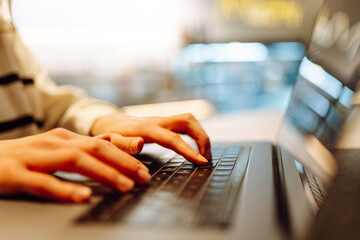 Close - up of woman's hands typing on laptop keyboard at home. Cyber security concept. Freelancer,...