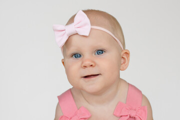Portrait of cute little blonde baby girl with pink bow on her head. Baby girl with big blue eyes.