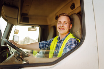 Handsome driver at the wheel of a truck at work. Driver or forwarder on truck and trailer, on a...