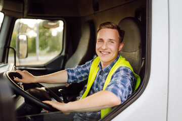 Handsome driver at the wheel of a truck at work. Driver or forwarder on truck and trailer, on a...