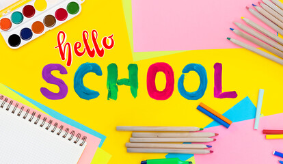Hello school background. Top view flat lay concept. Childish lettering, colored paper, supplies,...