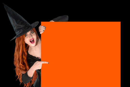 Witch on Halloween pointing with index finger. Female wizard fairy character for All Saints' Day. Fantasy gothic red-haired Vampire girl in black dress carnival costume.