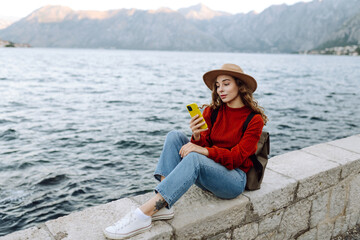 Young woman with phone on the embankment. Tourist during holidays. Lifestyle, travel, nature, active life.