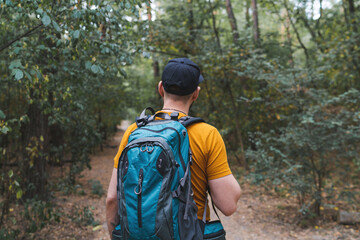 Young male tourist walking the forest path with big travel backpack
