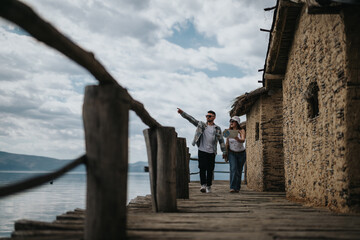 A happy couple sightseeing by a traditional lakeside structure, enjoying their holiday trip outdoors on a sunny day.