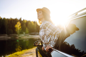 Relaxed woman leaning out car window during summer trip.  Lifestyle, travel, tourism, nature,...