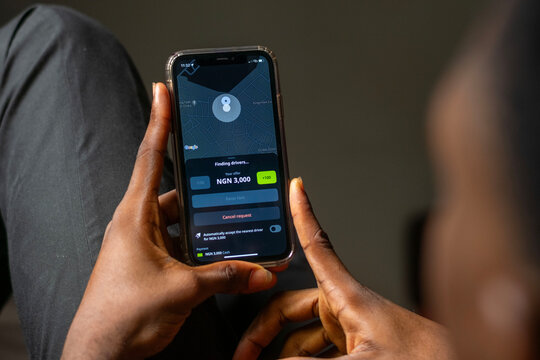 african man using Indrive apps on on Apple smartphone, guy trying to book a drive from his comfort zone.  Indrive is sharing-economy service for urban transport. Abuja, F.C.T, Nigeria - 26 April 2024