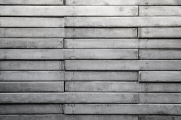 Front view of a wall made of gray concrete slates. Abstract high resolution full frame textured background in black and white, copy space.
