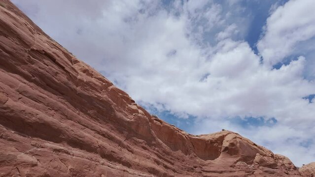 View of sandstone cliffs in the Escalante desert with fluffy clouds in the sky.