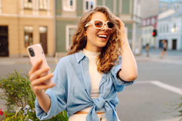 Cheerful female tourist clicking selfie pictures via cellphone front camera. Lifestyle, travel,...
