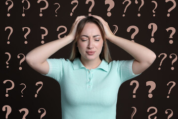 Amnesia. Confused young woman and question marks on brown background