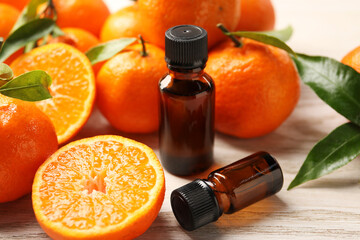 Bottles of tangerine essential oil and fresh fruits on wooden table, closeup