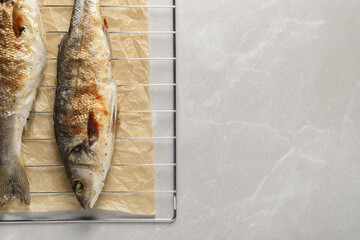 Baked fish on light marble table, top view. Space for text