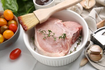 Raw meat, thyme, brush with marinade and products on light table, closeup