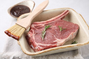Raw meat, rosemary and brush with marinade on light table, closeup