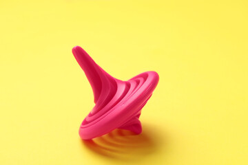 One pink spinning top on yellow background, closeup