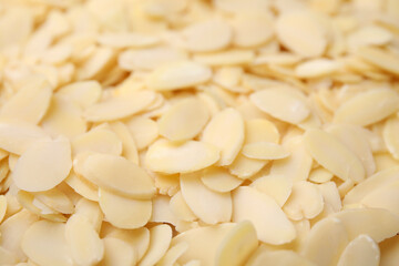 Fresh almond flakes as background, closeup view
