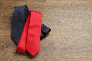 Red and blue neckties on wooden table, top view. Space for text