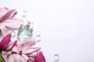 Beautiful pink magnolia flowers, bottle of perfume and ice cubes on white background, flat lay....