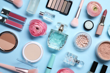 Flat lay composition with different makeup products and beautiful spring flowers on light blue...