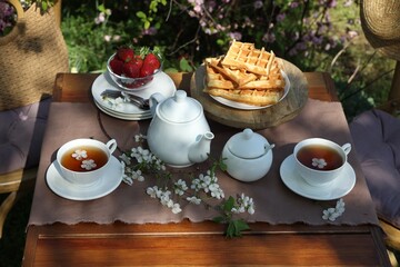 Beautiful spring flowers, freshly baked waffles and ripe strawberries on table served for tea...