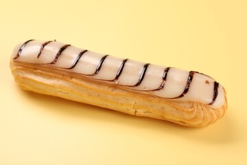 Delicious eclair covered with glaze on yellow background