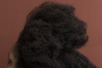 Black afro curly hair with shrinkage, Type 4c hair that is dry with a brown background