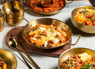 Chuncheon Fried Spicy Chicken with spoon and chopsticks served in golden dish isolated on wooden board side view of honk kong food