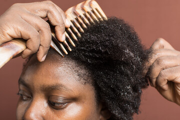 Combing black afro curly hair with shrinkage, using a wide tooth comb to detangle wet Type 4c hair