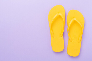 Bright yellow flip-flops on color background, top view. Summer concept