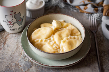Dumplings with cottage cheese and butter in a beautiful breakfast plate on a gray background....