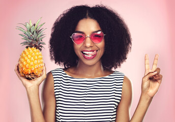 Peace sign, portrait and black woman with pineapple, studio or detox on pink background. Health,...