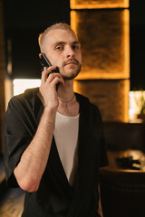 Focused blond man listens to boss recommendations over smartphone. Responsible employee receives...