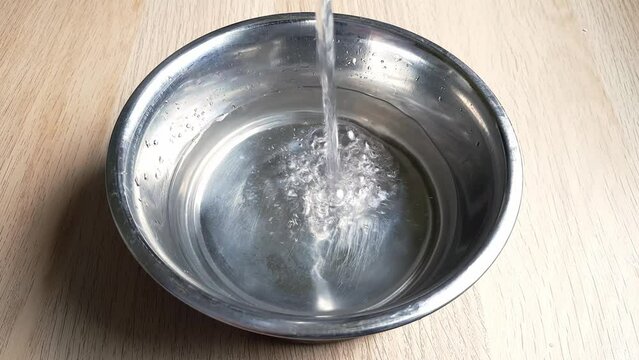 Water is poured into dog's bowl. Drinking regime and caring for health of pet.