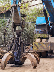 Machine, loader manipulator with hydraulic grappling claw collecting, moving old steel, scrap metal.